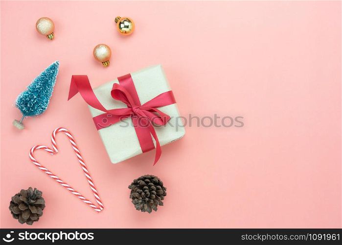 Table top view of Merry Christmas decorations & Happy new year ornaments concept.Flat lay essential difference objects gift box & fir tree on modern pink paper background at home studio office desk.