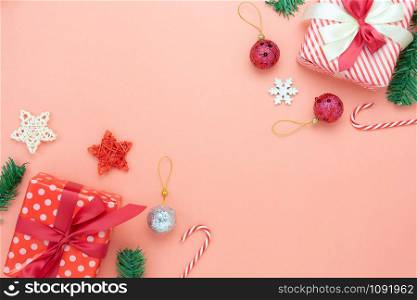 Table top view of Merry Christmas decorations & Happy new year ornaments concept.Flat lay essential difference objects gift box & fir tree on modern pink paper background at home studio office desk.