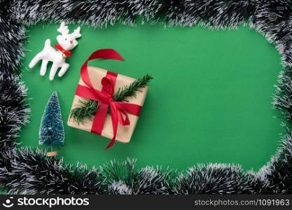 Table top view of Merry Christmas decorations & Happy new year ornaments concept.Flat lay essential difference objects gift box & fir tree with reindeer on modern green paper background.Space design.