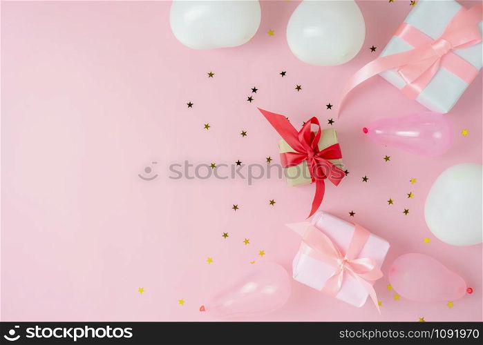 Table top view of Merry Christmas decorations & Happy new year ornaments concept.Flat lay essential difference objects gift box & balloon with confetti golden star on modern pink paper background.