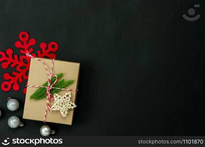 Table top view of Merry Christmas decorations & Happy new year ornaments concept.Flat lay essential difference objects gift box & fir tree on modern black paper background at home studio office desk.