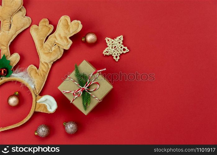 Table top view of Merry Christmas decorations & Happy new year ornaments concept.Flat lay essential difference objects gift box & fir tree on modern red paper background at home studio office desk.