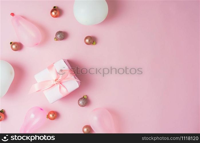Table top view of Merry Christmas decorations & Happy new year ornaments concept.Flat lay essential objects the baubles & gift box on modern rustic pink paper background at home studio office desk.