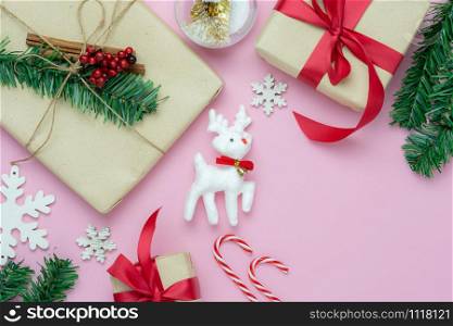 Table top view of Merry Christmas decorations & Happy new year ornaments concept.Flat lay essential objects the reindeer & gift box on modern rustic pink paper background at home studio office desk.