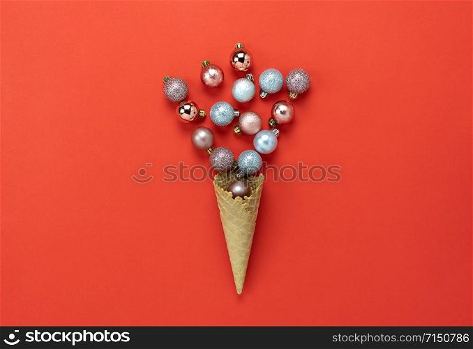 Table top view of Merry Christmas decorations & Happy new year ornaments concept.Flat lay essential difference objects baubles & ice cream cone laying on modern red paper background at office desk.
