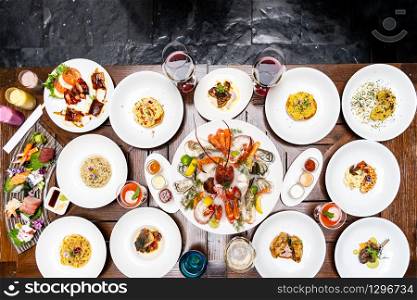 Table top view premium variety of international food in restaurant of lobster shrimp steak beef lamb pasta spaghetti risotto rice sushi sashimi and wine using for buffet food drink background.