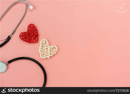 Table top view shot of arrangement equipment medical background concept.Red heart & stethoscope on modern rustic pink paper.An idea essential accessories for doctor for care patient in hospital.