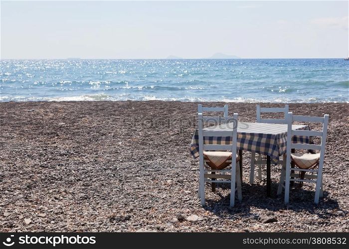 Table with chairs on the beach. Tavern, restaurant in Greece, Santorini.