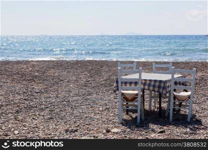 Table with chairs on the beach. Tavern, restaurant in Greece, Santorini.