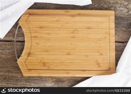 table with empty wooden cutting board and cloth napkin