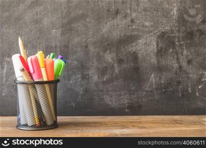 table with pencil cup near blackboard