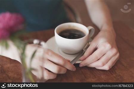 table with pink flower, women in cafe, cup and heands part of the body shot, closeup