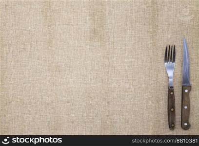 Tablecloth of burlap, fork,knife for steak and napkin . Is used to create a menu for the steak restaurant.The background for the menu.