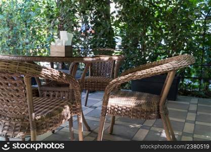 tables and wicker chairs in outdoor summer cafe with flower beds. outdoor summer cafe
