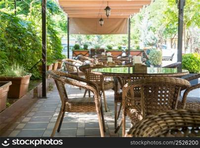 tables and wicker chairs in outdoor summer cafe with flower beds. outdoor summer cafe