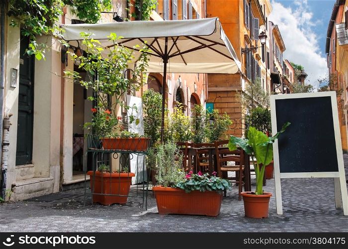 Tables outdoor cafe on a narrow street in Rome, Italy
