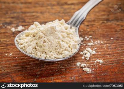 tablespoon of gluten free quinoa flour against rustic wood