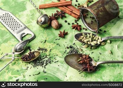 tablespoons with spices. spices and ingredients for Indian masala tea on green background