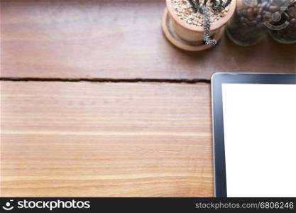 tablet, cactus pot and coffee bean in bottle on wooden desk - top view