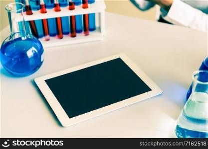Tablet computer in laboratory and biochemistry sample in test tube. Science technology research and development study concept.