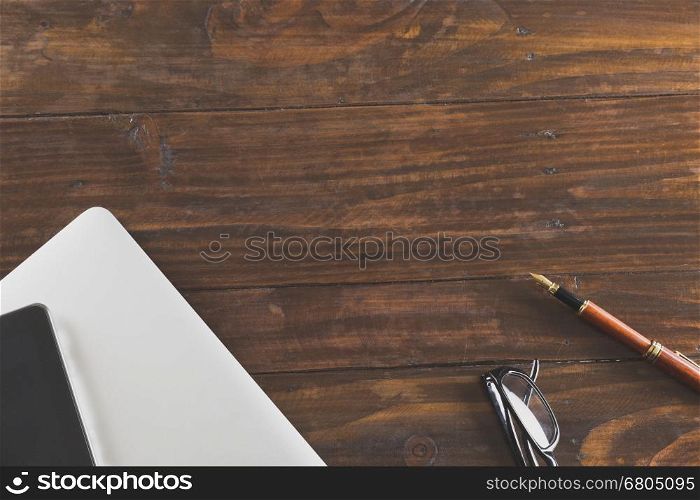 tablet, computer notebook and pen on wooden office desk - top view