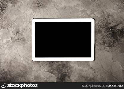 Tablet computer on grey stone background. Top view. Flat lay style.