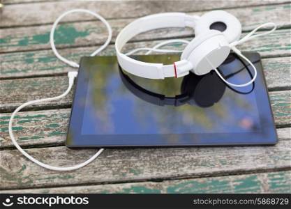 Tablet computer with headphones against wooden background
