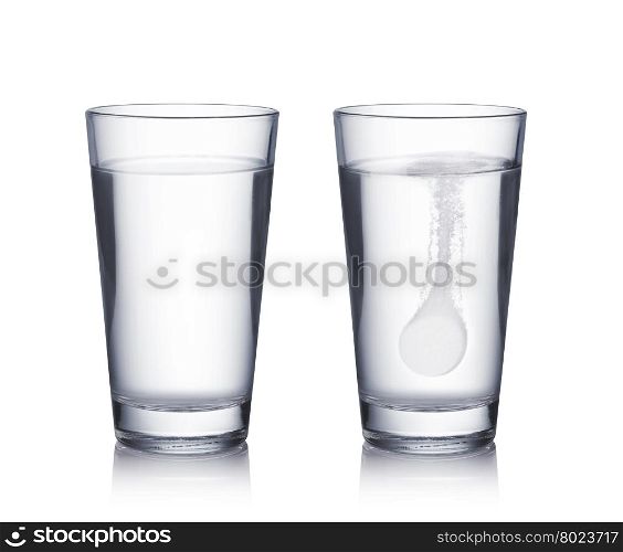 Tablet dropped into the water. Glass with effervescent tablet in water with bubbles on white background