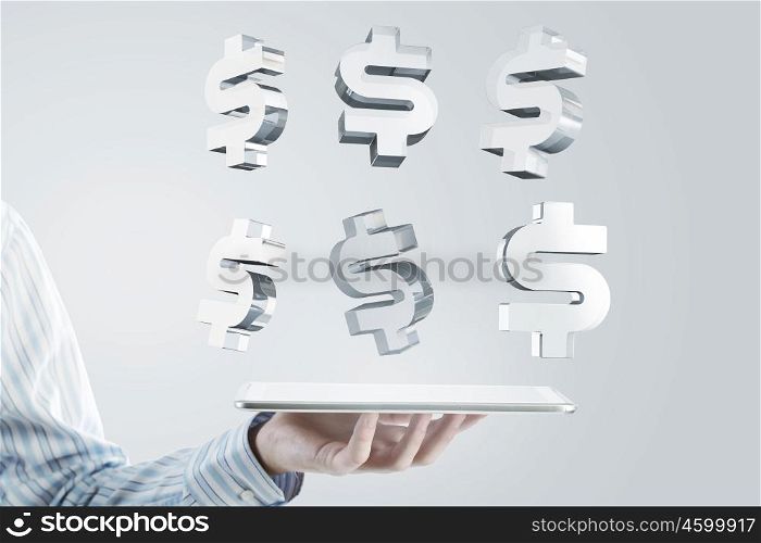 Tablet in hand with symbols. Close up of businessman hand holding tablet and glass dollar symbols