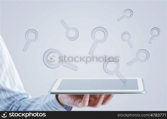 Tablet in hand with symbols. Close up of businessman hand holding tablet and glass symbols