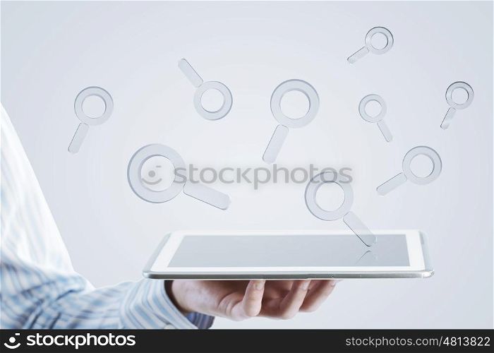 Tablet in hand with symbols. Close up of businessman hand holding tablet and glass symbols