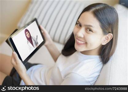 Tablet monitor view over girl shoulder, A Muslim doctor woman is wearing uniform and give consultation to young women, Health care technology concept