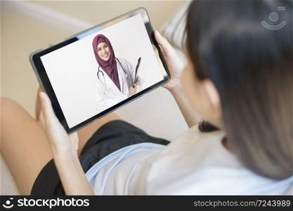 Tablet monitor view over girl shoulder, A Muslim doctor woman is wearing uniform and give consultation to young women, Health care technology concept