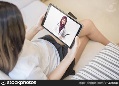 Tablet monitor view over girl shoulder, A Muslim doctor woman is wearing uniform and give consultation to young women, Health care technology concept