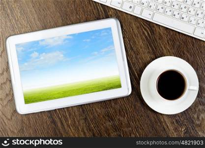 Tablet pc cup of coffee and keyboard at table. Office workplace