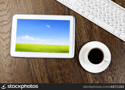 Tablet pc cup of coffee and keyboard at table. Office workplace