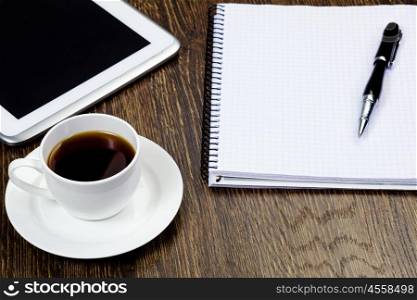 Tablet pc cup of coffee and notepad at table. Work place