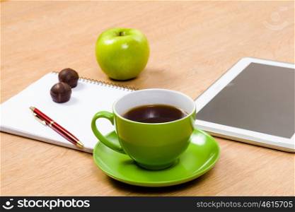 Tablet pc cup of coffee and notepad at table. Work place