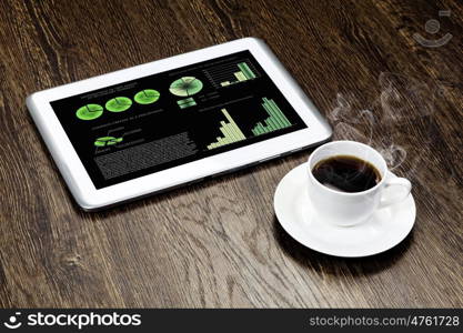 Tablet pc cup of coffee and notepad at table. Work place