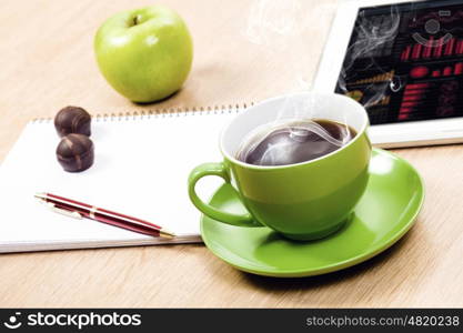 Tablet pc cup of coffee and notepad at table. Work place