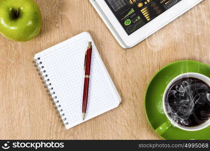 Tablet pc cup of coffee and notepad at table. Work place