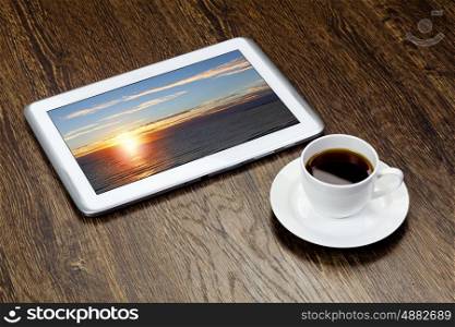 Tablet pc cup of coffee on wooden table. Work place