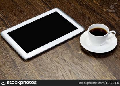 Tablet pc cup of coffee standing on wooden table. Work place