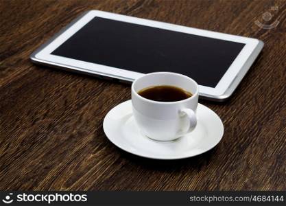 Tablet pc cup of coffee standing on wooden table. Work place