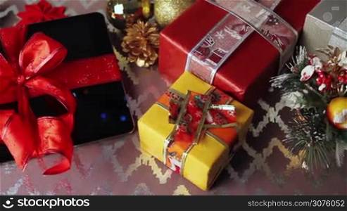 Tablet pc for Christmas with gifts, decorations on table.