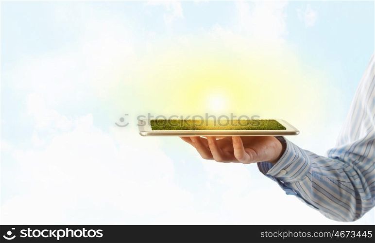 Tablet pc in hand. Hand holding tablet pc with green grass on screen