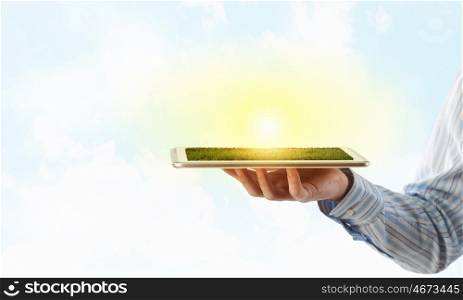 Tablet pc in hand. Hand holding tablet pc with green grass on screen