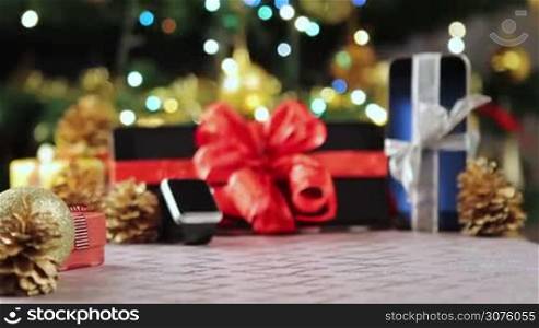 Tablet pc, smartphone and smartwatch as gifts in front of Christmas tree with lights.