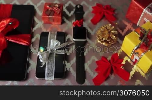 Tablet pc, smartphone and smartwatch for Christmas with gifts and decorations on table.