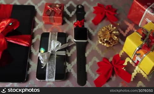 Tablet pc, smartphone and smartwatch for Christmas with gifts and decorations on table.